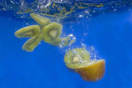 fresh kiwi splashing in waterの写真素材
