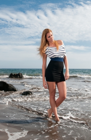 Blonde girl wearing saylor clothes at the seasideの写真素材