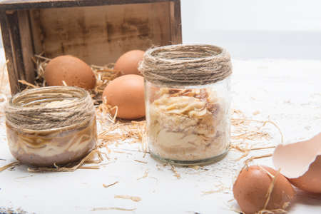 chicken eggs in a box with straw on the tableの写真素材