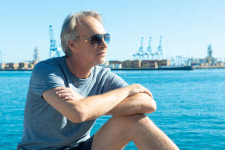 attractive mature man strolling through the marina of a European city