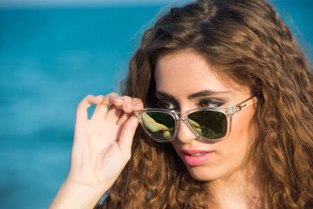 blonde woman with long curly hair enjoying the sea in spring or summerの写真素材