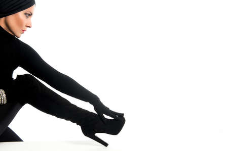 elegant woman made up and dressed in black with turban and gloves on a white background with copy spaceの写真素材