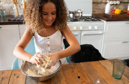 African American girl in her home kitchen making a pastry dough