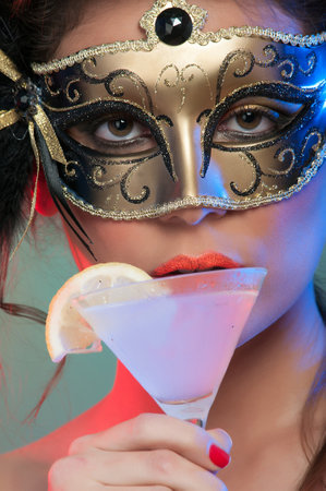 sensual woman with colorful carnival mask and makeup with a cocktailの写真素材
