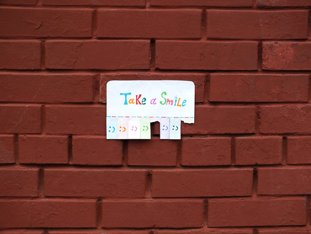 A paper with the phrase: Take a Smile and with a smile sign ready to be tore off