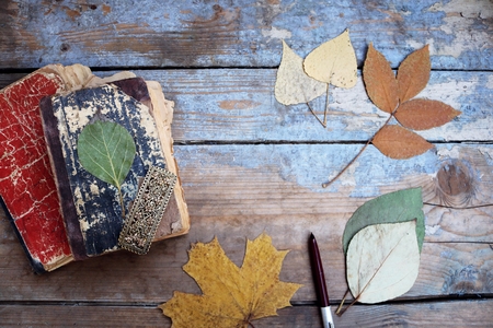 Vintage books and autumn leaves on wooden deskの写真素材