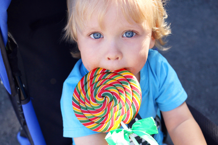 Toddler eating a yummy colorful lollipop. Baby boy with swirl lollipopの写真素材