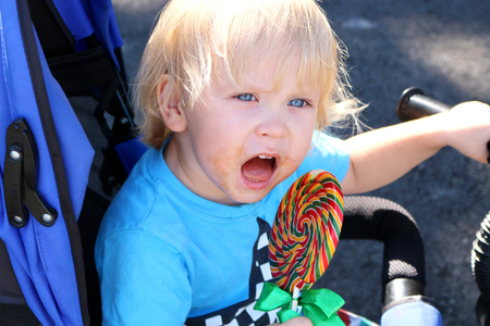 Toddler eating a yummy colorful lollipop. Baby boy with swirl lollipopの写真素材