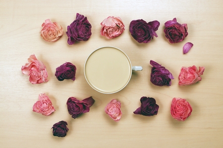 Hearts, wilted flowers and cup of coffee on pastel wooden background.の写真素材