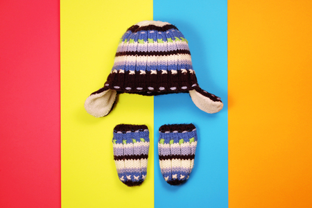 Knitted hat and mittens on multicolored backgroundの写真素材