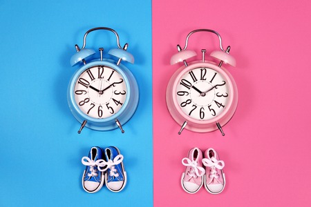 Two alarm clocks on blue pink background, twins conceptの写真素材