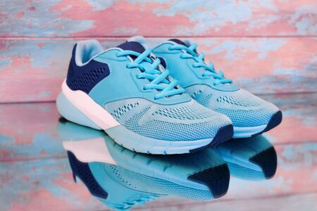 Blue sport shoes on blue and pink background. Female sneakers on wooden background with copy space. Running shoes with reflection in the mirrorの写真素材