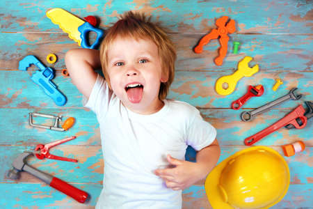Cute little boy surrounded by toy tools top view. Happy boy playing with a toy tools set . Early childhood education conceptの写真素材