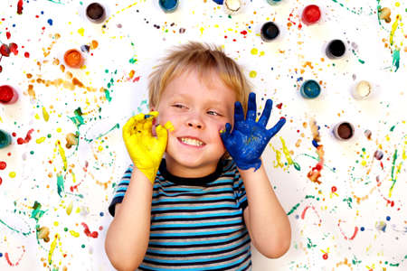 Happy cute dirty boy child playing with paint on colorful background. Drawing conceptの写真素材