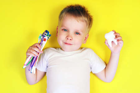 Cute boy child kid on yellow background. Teeth cleaning, oral care, dental hygiene conceptの写真素材