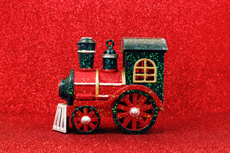 Toy steam train locomotive on red glitter background. Christmas tree toyの写真素材