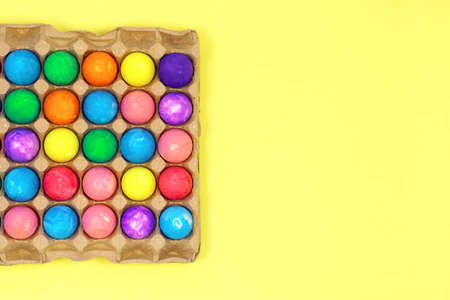 Many multicolored easter eggs in egg box on yellow background top view copy spaceの写真素材