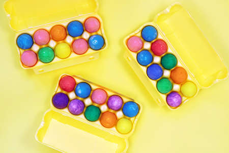 Thirty multicolored easter eggs in yellow egg boxes on yellow background top view copy spaceの写真素材