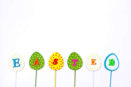 Word Easter isolated on white background, copy space, minimalism. Inscription Easter on multicolored...