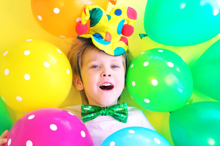 Funny laughing child clown with multicolored balloons. Birthday party concept. April fools day celebration concept.の写真素材