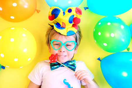 Funny smiling child clown with multicolored balloons. April fools day celebration concept. Birthday party concept.の写真素材