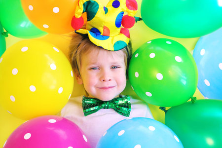 Cute smiling child clown with multicolored balloons. Birthday party concept. April fools day celebration concept.の写真素材