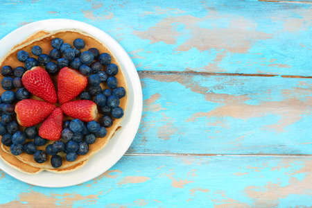 Delicious pancakes with blueberry and strawberry on blue wooden table, top view copy spaceの写真素材