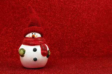Cute Snowman figurine on red glitter background with copy space. Happy New year and Christmas 2022 celebration.の写真素材
