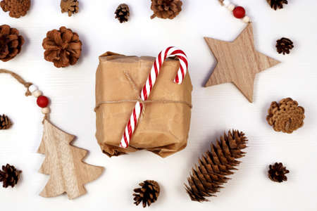 Christmas gift box wrapped in craft recycled paper, white wooden background. zero waste eco friendly packaging.の写真素材