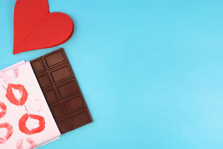 Chocolate bar wrapped in white paper with lipstick kiss prints. top view, copy space. Sweet tooth concept. Valentines day greeting cardの写真素材