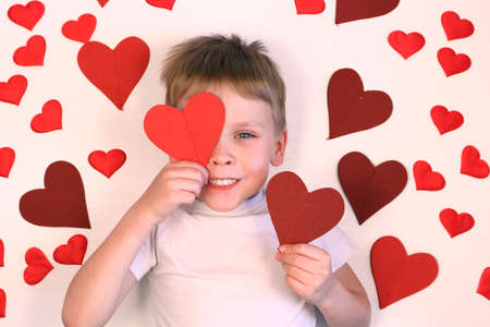 Cute little boy holding red heart for valentines day. Smiling child kid with red hearts on white background.の写真素材