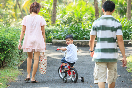 Samut Prakan, Thailand â NOVEMBER 25, 2012: Young boy enjoying riding bike with family in the garden. Summer time. Phra Pradaeng District.のeditorial素材
