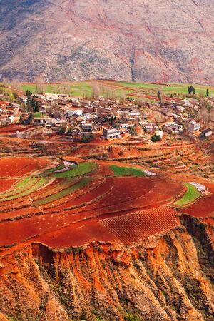 Fantastic landscape, colorful scenic old village of Red Land at sunrise, red mountain backgrounds. The sun shines down around terraced wheat fields. Dongchuan, China. Spring season. Bright sunlight.の写真素材