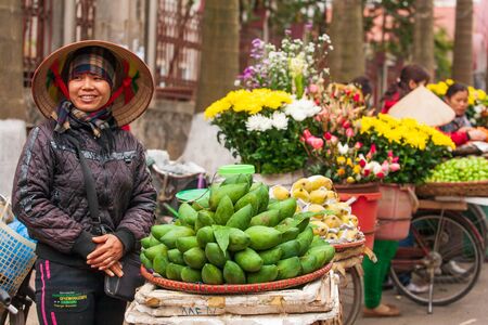 Lao Kai, Vietnam %u2013 FEBRUARY 29, 2012: Street vendors with bicycles on the street at Vietnam-China border. Vietnamese woman street vendor's with Non La or Vietnam hat standing and smiling at the camera. Lao Kai.のeditorial素材