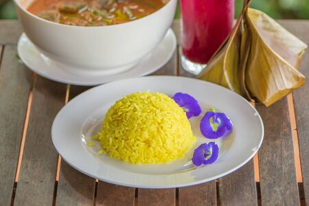 Turmeric Rice and Butterfly pea on white plate. Tradition Thai food on a wooden table. Thai style. Shallow dept of field. Close. Soft sunlight.の写真素材