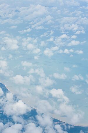 Aerial sky and abstract white clouds from airplane window, beautiful curve of gulf and blue sea...