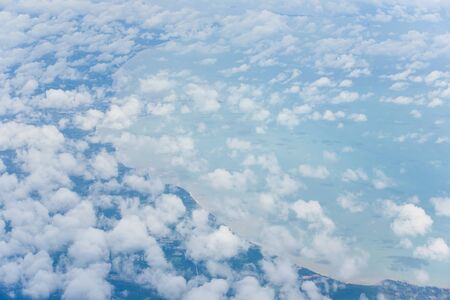 Aerial sky and abstract white clouds from airplane window, beautiful curve of gulf and blue sea...