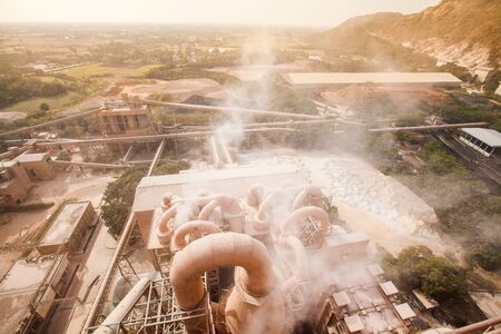 Top view of cement factory, dusty and steam was blowing in the factory, village and mountain in the dust in the evening, hot weather. Dust and grain.の写真素材