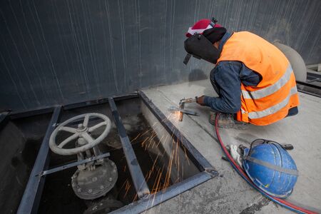 Male welder is welding new steel grate, arc welding process with sparks. Industrial worker concept. Long exposure.の写真素材