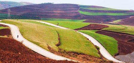Beautiful rural scenery in South China, Red Land of Dongchuan. Local chinese men riding motorcycle...