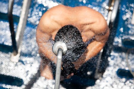 Top view of bare-chested man showering under refreshing freshwater on the cruise ship, abstract transparent with bokeh on freshwater, bright sunny summer. Selective focus.の写真素材