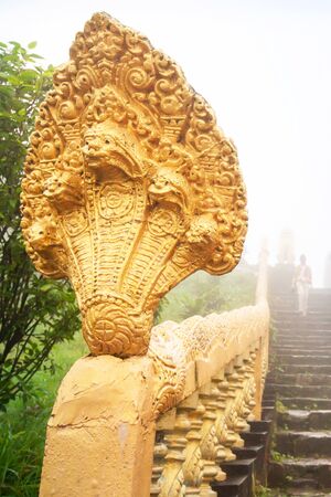 Ancient golden Naga stairs and buddhist tourist in blue misty. Wat Sampov Pram, Kampot, Cambodia. The temple is open to the public.の写真素材