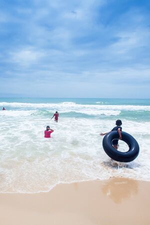 A group of Khmer teenage girls playing in the waves on the Ochheuteal Beach in a rainy day, top tourist attraction in South Cambodia.の写真素材