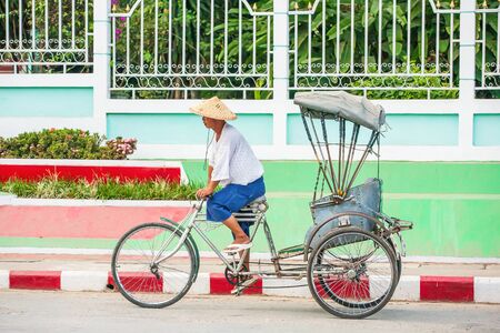 Shan State, Myanmar - DECEMBER 1, 2010: Myanmar man cycling rickshaw on the township alley. Tachileik market.のeditorial素材