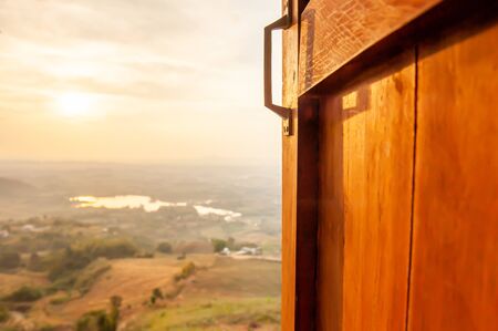 Open window view onto a tranquil morning with the sun shines on a lake blurred background, scenery on wonderful morning from home window. Focus on old wooden window.の写真素材