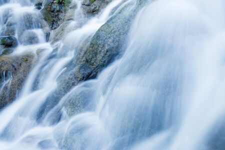 Close shot of freshwater of tropical waterfall pouring on limestone in rainy season, pure water flowing on layers of limestone wall. Long exposure.の写真素材