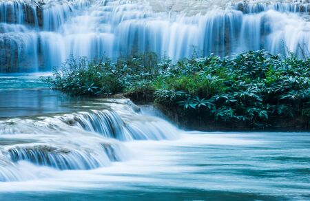 Relaxing by a tropical waterfall in the morning, gently freshwater flowing on limestone layers. Long exposure.の写真素材