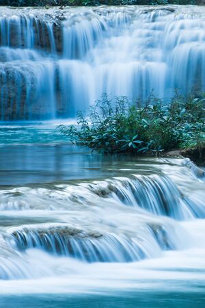Relaxing by a tropical waterfall in the morning, gently freshwater flowing on limestone layers. Long exposure.の写真素材