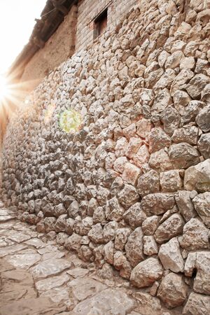 Ancient stone wall texture of Chengzi Village in Yunnan, South China. The sun setting on ancient stone wall and stone alley.の写真素材