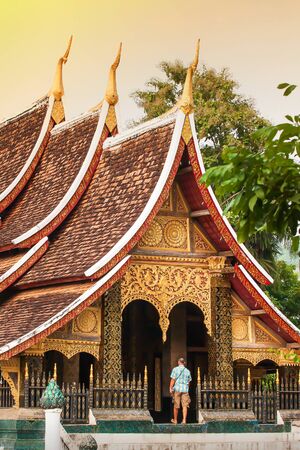 Elegant ancient buddhist temple of Wat Xieng Thong, a senior European tourist appreciating the ancient temple, travel destinations in Luang Prabang, Laos.の写真素材